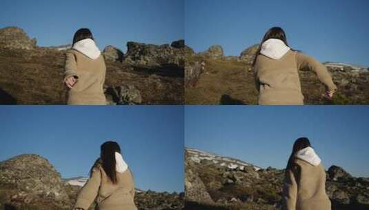 一个穿着米色夹克和连帽夹克的女孩在高山上奔跑高清在线视频素材下载