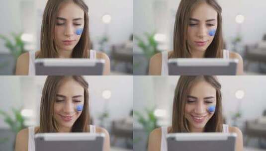 年轻可爱女人坐在家里，看着平板电脑微笑的特写肖像高清在线视频素材下载
