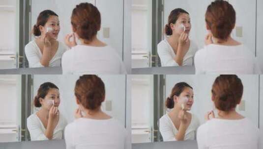 美女对着镜子在脸上涂抹化妆品高清在线视频素材下载