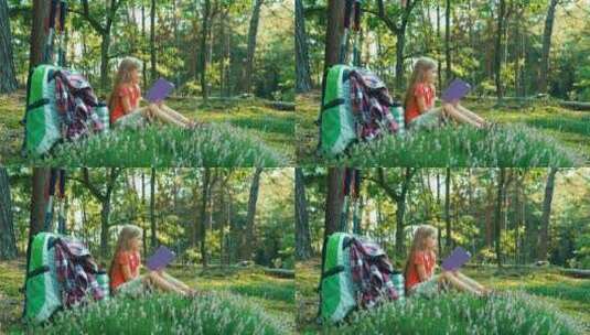 孩子坐在森林里的草地上看书高清在线视频素材下载