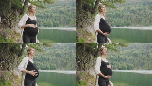 孕妇站在山湖附近轻轻抚摸肚子高清在线视频素材下载