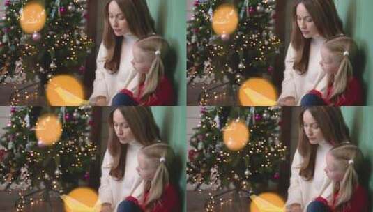 母亲在圣诞树旁给孩子阅读高清在线视频素材下载