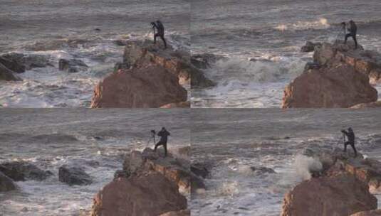 冬季海边礁石上的摄影师在风浪中拍摄高清在线视频素材下载