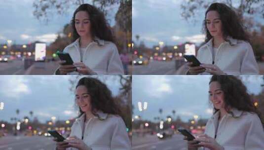 快乐的年轻女子在街上使用智能手机，背景是高清在线视频素材下载
