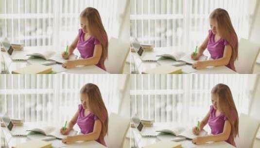 女孩坐在桌子上写练习册高清在线视频素材下载