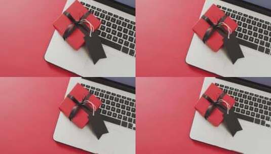 笔记本电脑和带黑色丝带和礼品标签的红色礼品盒，红色背景，带复制空间高清在线视频素材下载