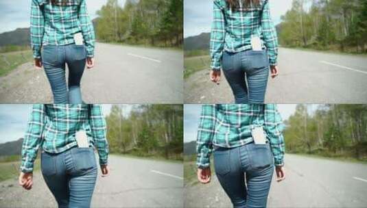 穿着牛仔裤走在路上的女人的后视图高清在线视频素材下载