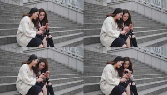 两位美女坐在台阶上看手机开心聊天高清在线视频素材下载