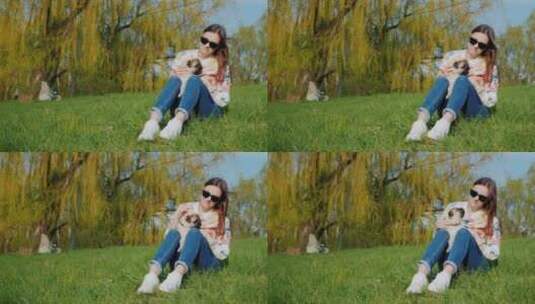 年轻女子抱着狗狗坐在绿色草坪上休息高清在线视频素材下载