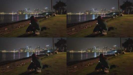 夜晚一个孤独女孩在海边坐着思考玩手机高清在线视频素材下载