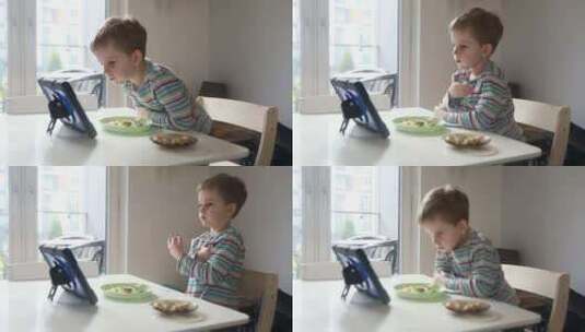 年轻男孩在明亮的厨房吃早餐时全神贯注于看高清在线视频素材下载