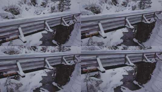 冬季仙境。阿尔卑斯山上有一条小溪的雪谷。无人机正在下降到一座桥前高清在线视频素材下载