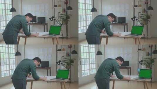 男士在绿屏笔记本电脑旁的纸上绘画高清在线视频素材下载