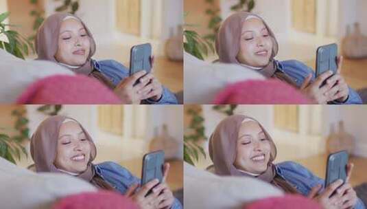 戴头巾微笑的女人在沙发上使用手机高清在线视频素材下载