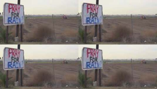 一辆拖拉机犁地和一个牌子上写着祈祷下雨高清在线视频素材下载