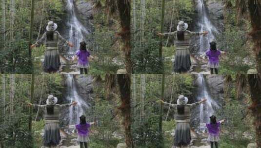 妈妈与女儿一起拥抱大自然背影 面对瀑布高清在线视频素材下载