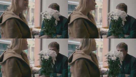 咖啡馆约会时，一对年轻男女深情对视的慢动作片段。手持白花的女孩。浪漫时刻高清在线视频素材下载