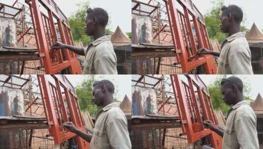 一个非洲黑人在他的焊接车间外面工作画了一扇红色的金属门高清在线视频素材下载