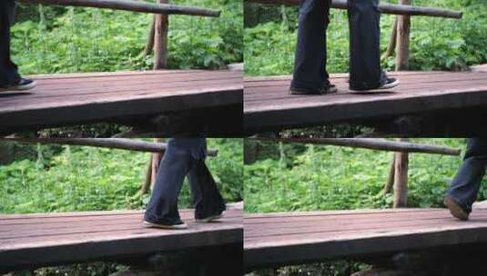 一个穿着深色宽裤子的女孩在树林里的木桥上慢动作过河高清在线视频素材下载