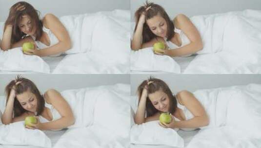 女孩拿着青苹果躺在床上对着镜头笑高清在线视频素材下载