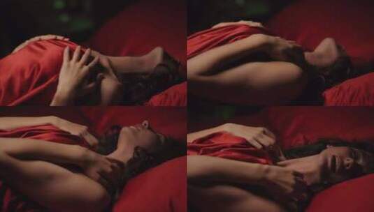 兴奋的女人在床上抚摸自己。躺在红色丝绸床高清在线视频素材下载