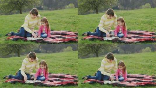 小女孩和妈妈一起在草地上读书高清在线视频素材下载