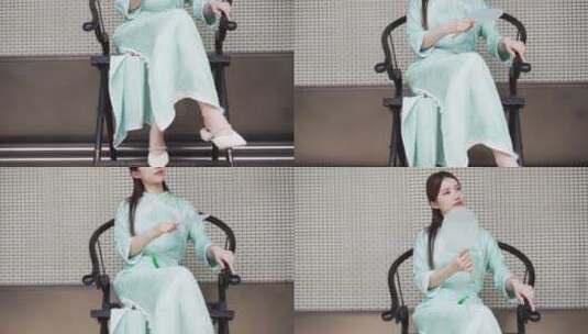 年轻旗袍女子摇着扇在中式合院门廊椅子休息高清在线视频素材下载