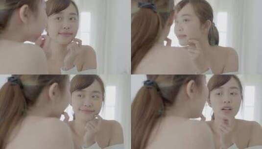 美丽的年轻亚洲女人微笑着看着健康检查皮肤护理高加索人的镜子。高清在线视频素材下载