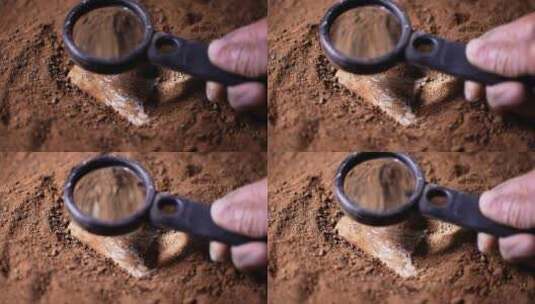 考古人员野外用放大镜观察研究埋在沙土文物高清在线视频素材下载