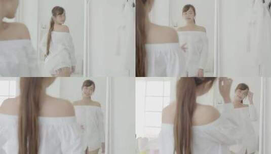 美丽的亚洲年轻女子微笑着装看着卧室的镜子。高清在线视频素材下载