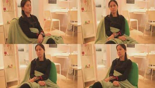 室内坐着盖毯子的女性高清在线视频素材下载