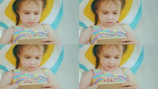女孩在游泳池边的躺椅上玩手机高清在线视频素材下载