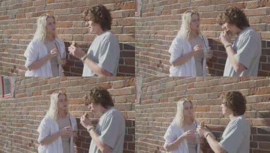 一对年轻夫妇靠砖墙聊天高清在线视频素材下载