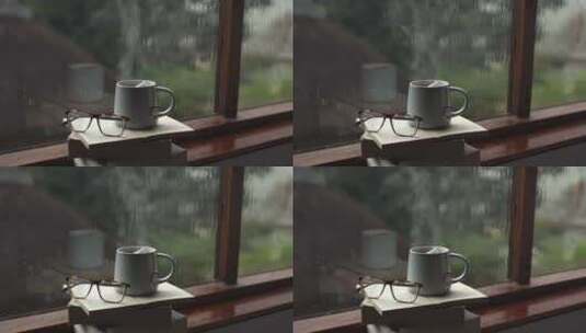 杯子泡着茶，和眼镜一起放在书上 窗外下雨高清在线视频素材下载
