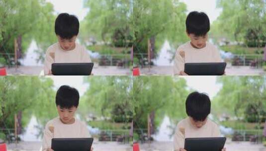 可爱的中国小男孩在户外使用平板电脑高清在线视频素材下载