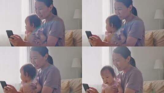 母亲抱着女儿看手机高清在线视频素材下载
