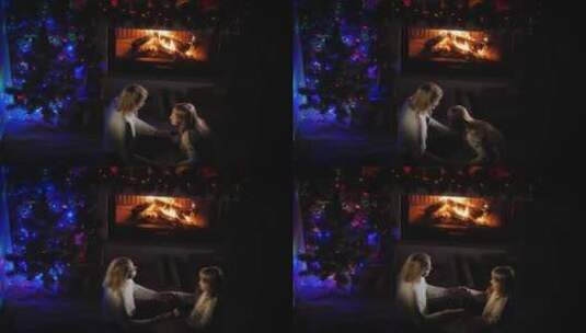 母亲和女儿在壁炉和圣诞树旁玩游戏高清在线视频素材下载