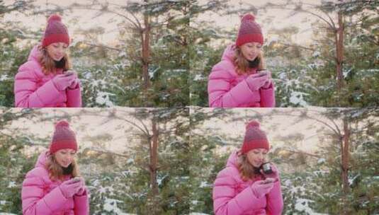 年轻女子在冬天的森林里使用手机高清在线视频素材下载
