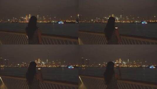 夜晚女人在海边拍摄城市景观高清在线视频素材下载