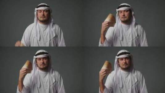 身着传统服装的成功阿拉伯谢赫在灰色背景下手里拿着钱高清在线视频素材下载