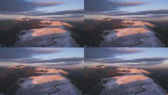日落时白雪覆盖的山脉，前景鸟瞰中蜿蜒的道路高清在线视频素材下载