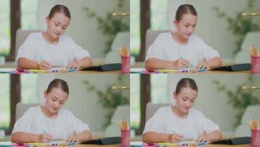 特写镜头专注于微笑的青少年女孩在办公桌上用绿色绒线笔在白纸上画画高清在线视频素材下载