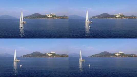 意大利马焦雷湖水域航行的白色帆船，背景是安吉拉城堡高清在线视频素材下载