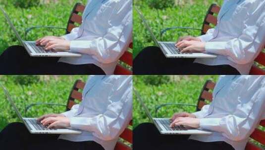 坐在公园长椅上使用笔记本电脑办公的美女高清在线视频素材下载