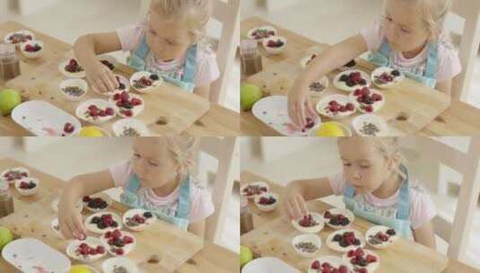 女孩把浆果放在桌子上的松饼上高清在线视频素材下载