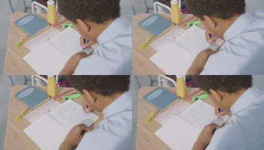男孩坐在书桌上写作业高清在线视频素材下载