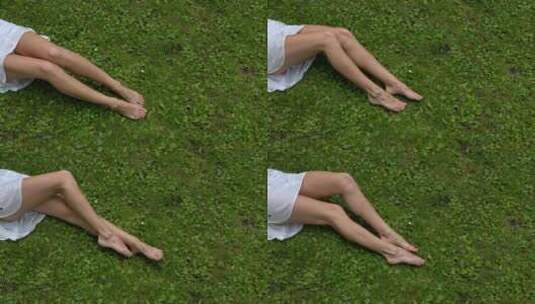 绿色草地上美丽的女性腿。夏天或春天草坪上的赤脚腿。高清在线视频素材下载