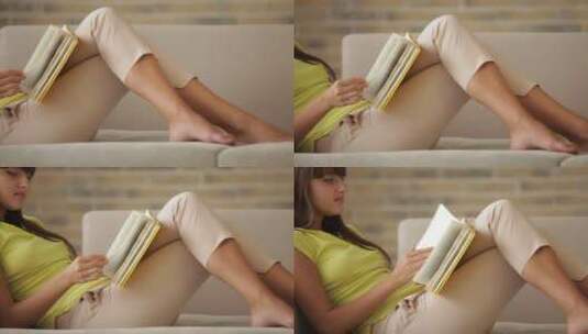美丽的女孩躺在沙发上阅读书籍高清在线视频素材下载