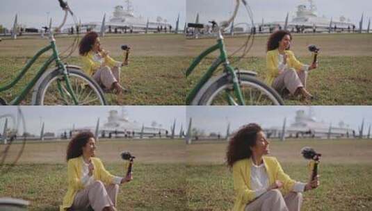坐在自行车旁边的草地上，卷发的拉丁女孩在高清在线视频素材下载