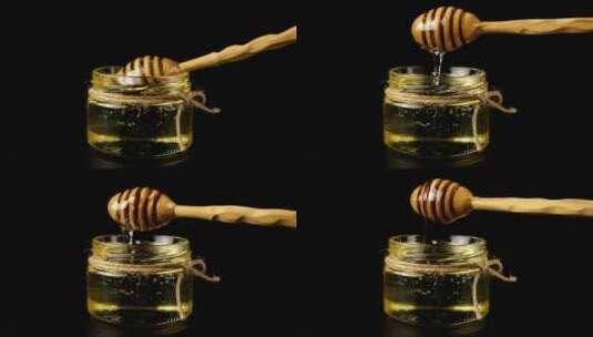黑色背景前蜂蜜从勺子上流下高清在线视频素材下载